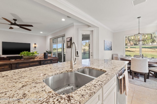 kitchen with crown molding, sink, hanging light fixtures, light stone countertops, and white cabinetry