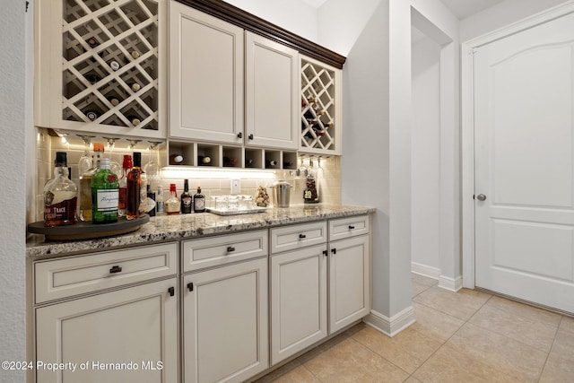 bar with backsplash, light stone counters, and light tile patterned floors