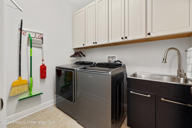 laundry area featuring cabinets, light tile patterned floors, washing machine and dryer, and sink