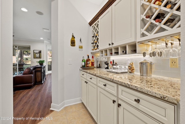 bar with backsplash, light stone counters, and lofted ceiling