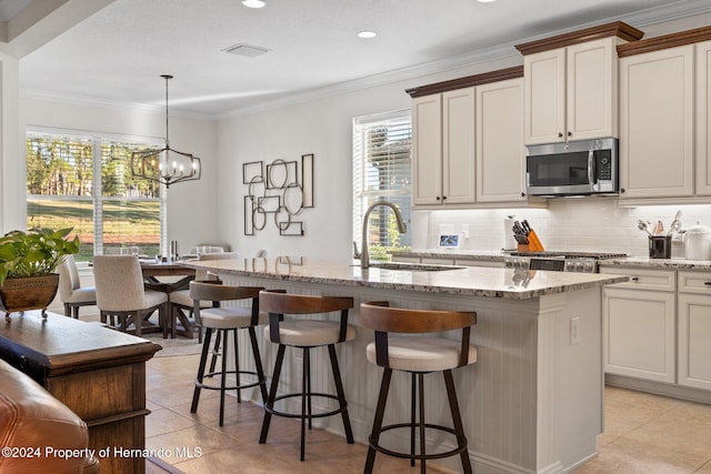 kitchen with pendant lighting, a center island with sink, sink, light tile patterned flooring, and a chandelier