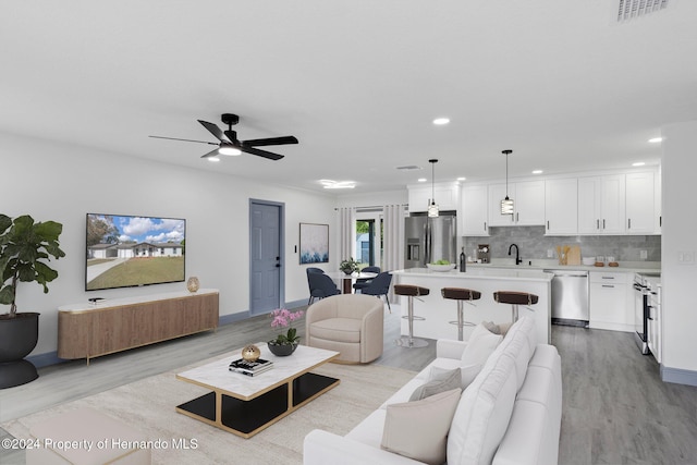 living room with ceiling fan, light hardwood / wood-style floors, and sink