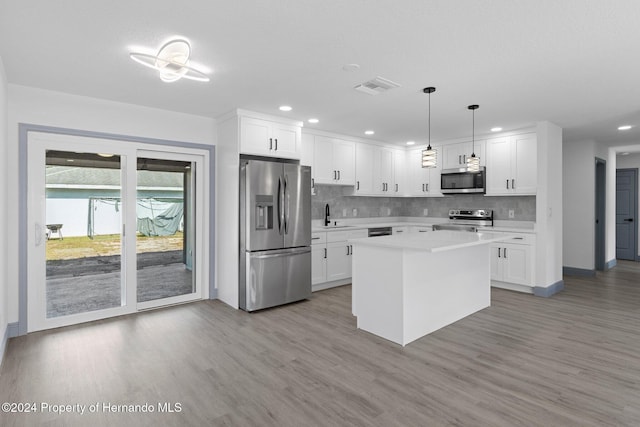 kitchen featuring white cabinets, decorative light fixtures, a center island, and stainless steel appliances