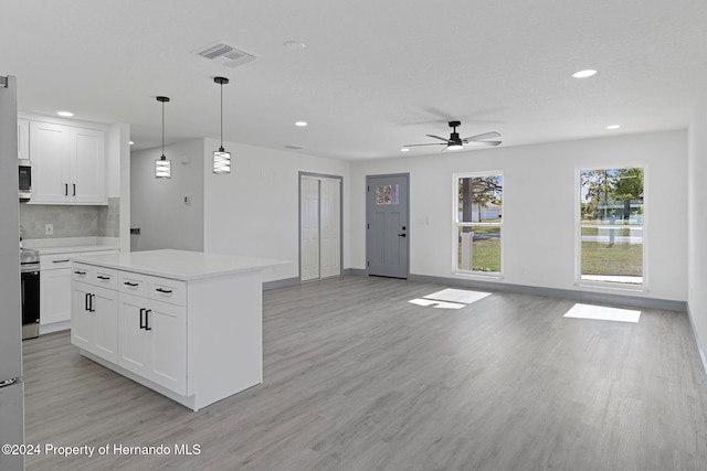 kitchen with white cabinetry, ceiling fan, hanging light fixtures, and a kitchen island