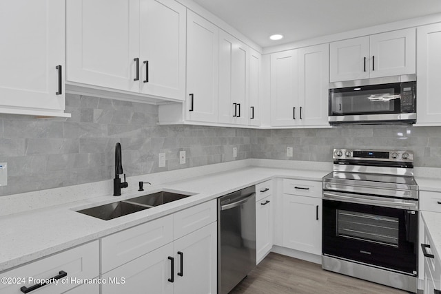 kitchen with white cabinets, decorative backsplash, stainless steel appliances, and sink