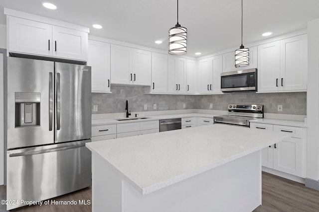 kitchen with decorative light fixtures, stainless steel appliances, white cabinetry, and sink