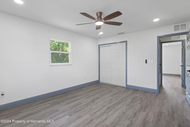 unfurnished bedroom with hardwood / wood-style floors, ceiling fan, and a closet