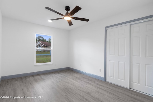 unfurnished bedroom featuring ceiling fan, light wood-type flooring, and a closet