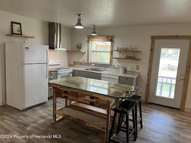 kitchen featuring hanging light fixtures, wall chimney exhaust hood, sink, white appliances, and a textured ceiling