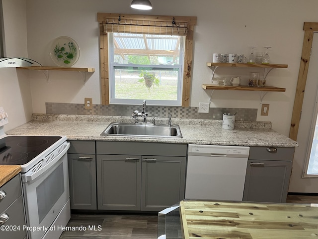 kitchen with sink, white appliances, wall chimney exhaust hood, and decorative backsplash