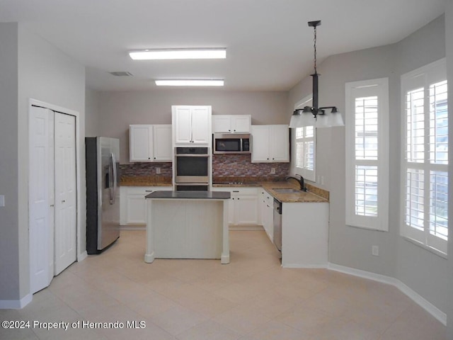 kitchen featuring decorative light fixtures, stainless steel appliances, white cabinetry, and sink