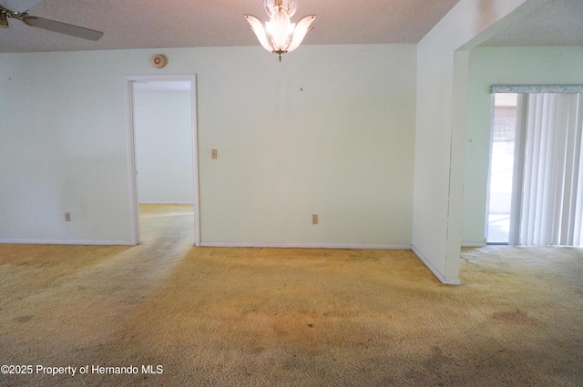 carpeted empty room with ceiling fan with notable chandelier