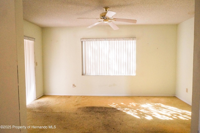 empty room with plenty of natural light, ceiling fan, a textured ceiling, and light carpet