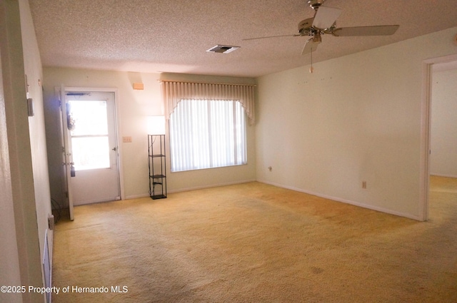 empty room with a textured ceiling, light colored carpet, and ceiling fan