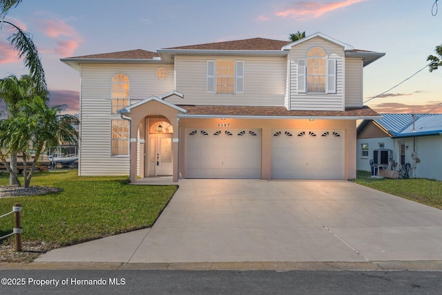 view of front property with a garage, central AC, and a lawn