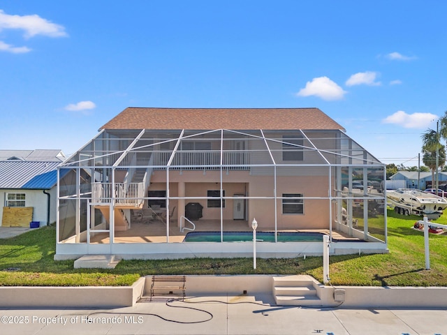 back of property with a lanai, a lawn, and a patio