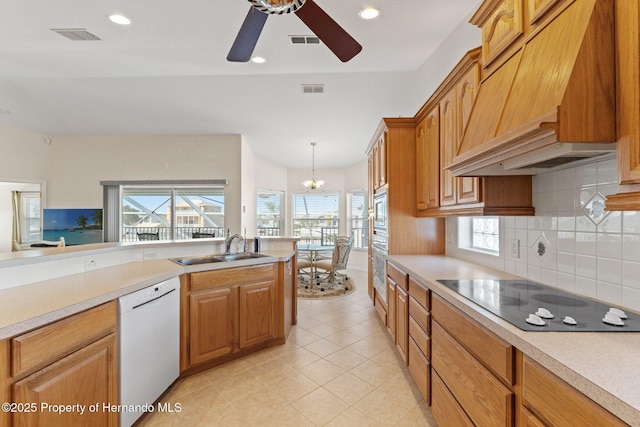 kitchen with pendant lighting, sink, premium range hood, appliances with stainless steel finishes, and backsplash