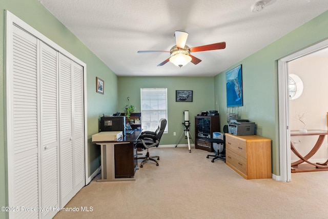 carpeted office space with a textured ceiling and ceiling fan