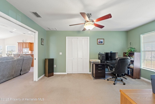 home office featuring ceiling fan, vaulted ceiling, and light carpet