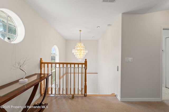 hallway with a chandelier and light carpet