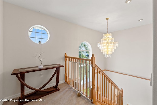 hallway with an inviting chandelier and carpet floors