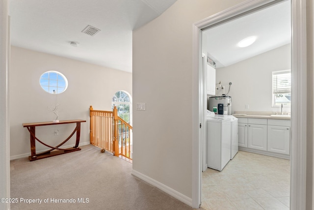 laundry room featuring washer and dryer, water heater, sink, cabinets, and light colored carpet