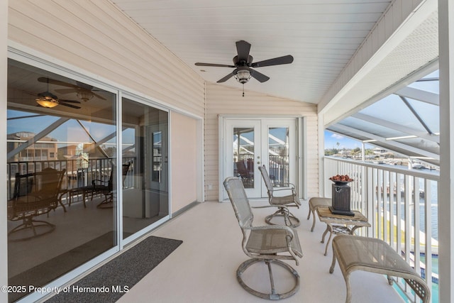 sunroom / solarium with a water view, ceiling fan, lofted ceiling, and french doors