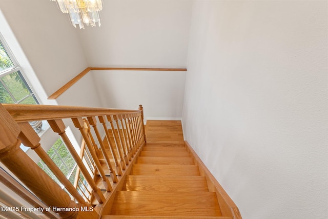 stairway with hardwood / wood-style flooring and a chandelier