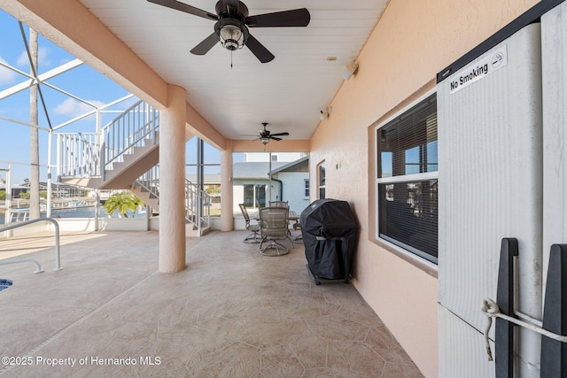 view of patio featuring ceiling fan, a grill, and glass enclosure