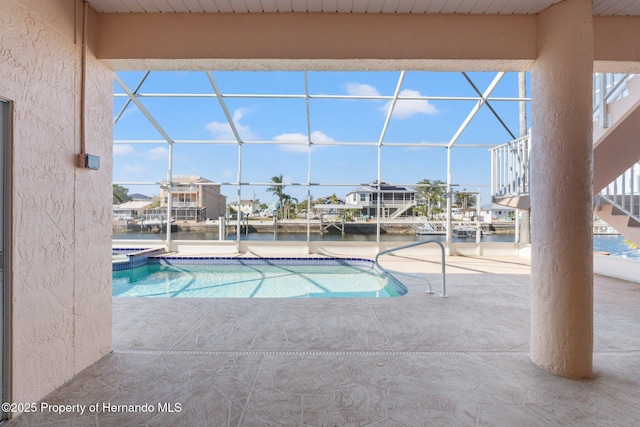 view of swimming pool with a patio, a water view, and a lanai