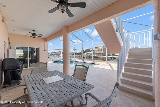 view of patio featuring a water view, grilling area, a lanai, and ceiling fan