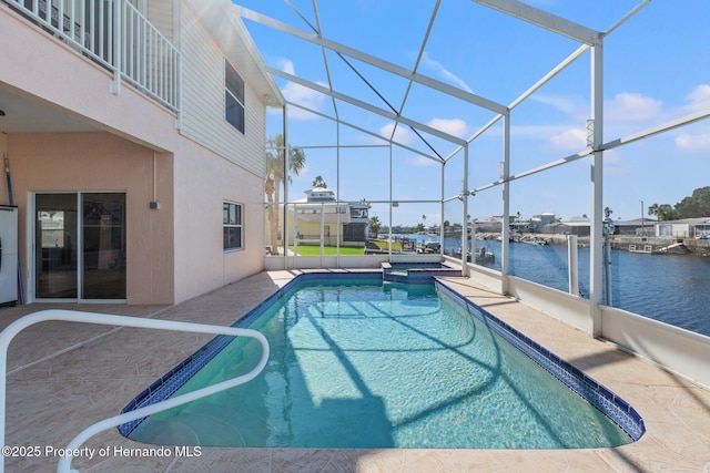 view of pool with a water view, an in ground hot tub, a patio area, and glass enclosure