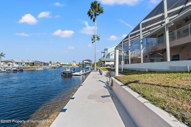 view of dock featuring a lanai, a yard, and a water view