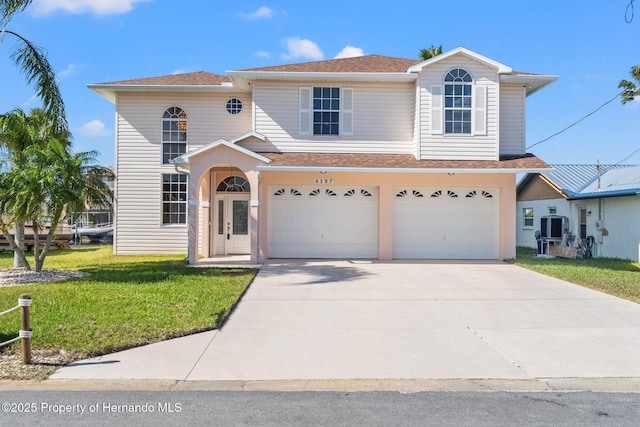 view of front of house with a garage, a front yard, and central AC unit