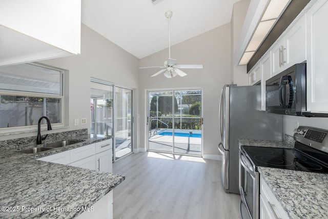 kitchen featuring stainless steel electric range oven, white cabinets, dark stone counters, and sink