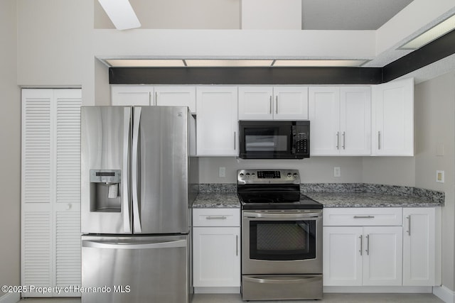 kitchen with appliances with stainless steel finishes, dark stone counters, and white cabinetry