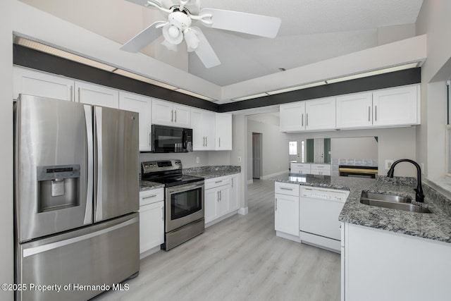 kitchen featuring sink, white cabinets, appliances with stainless steel finishes, and lofted ceiling