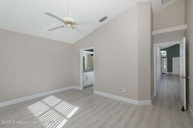 unfurnished bedroom featuring ceiling fan, high vaulted ceiling, ensuite bathroom, and light hardwood / wood-style flooring