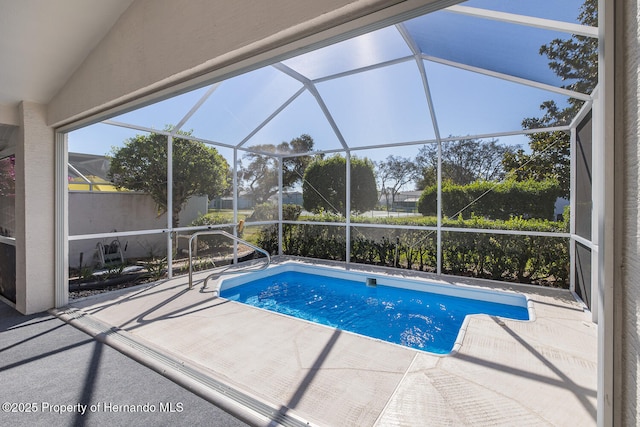 view of pool with glass enclosure and a patio area