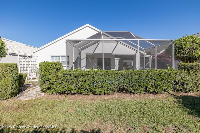 rear view of house with a yard and glass enclosure