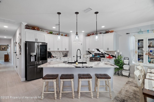 kitchen with appliances with stainless steel finishes, backsplash, sink, pendant lighting, and white cabinets