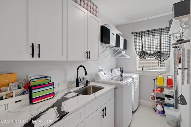 laundry area featuring washing machine and clothes dryer, sink, and cabinets