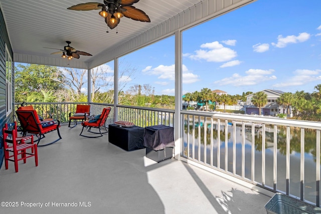 sunroom with a water view and ceiling fan