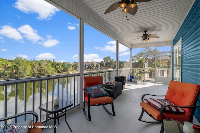 sunroom with ceiling fan and a water view