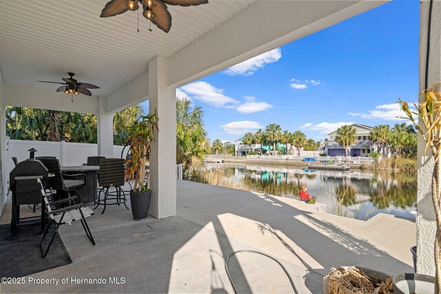 view of patio / terrace featuring ceiling fan, a water view, and a bar