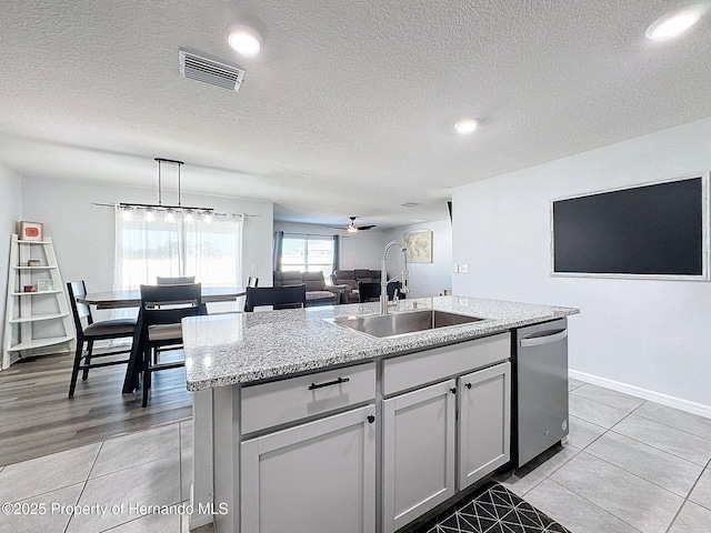 kitchen with ceiling fan, sink, stainless steel dishwasher, an island with sink, and decorative light fixtures