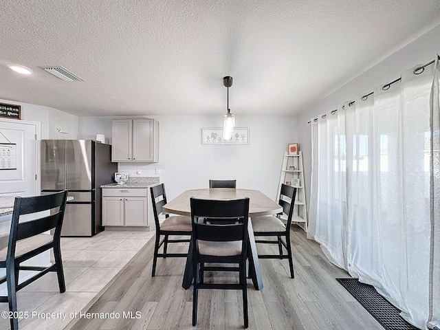 dining area with light hardwood / wood-style floors and a textured ceiling