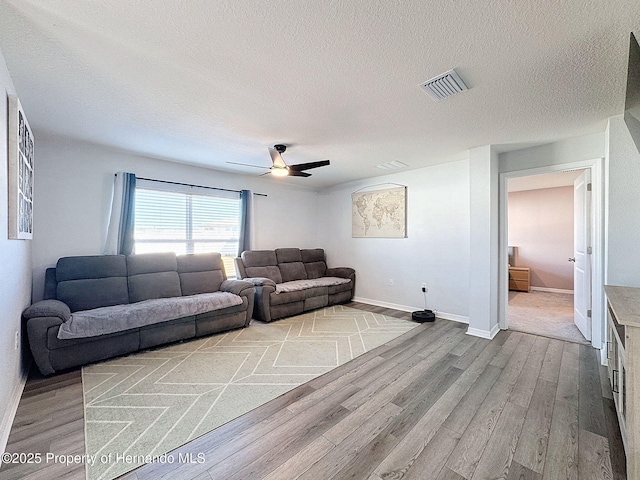 living room featuring a textured ceiling, light hardwood / wood-style flooring, and ceiling fan