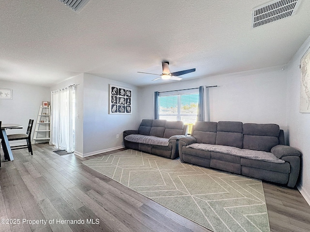 living room featuring ceiling fan, hardwood / wood-style floors, and a textured ceiling