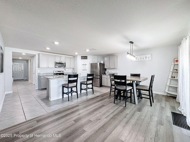 dining area featuring a textured ceiling and light hardwood / wood-style flooring